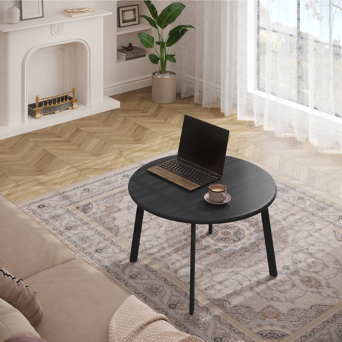 Ronde zwarte metalen salontafel in een woonkamer, met laptop en kopje op het blad