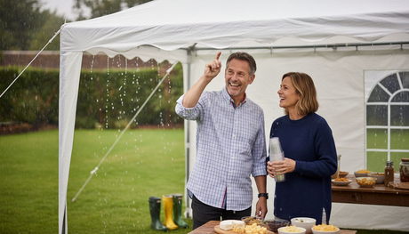 Een stel geniet samen van het feest onder een stevige partytent, terwijl buiten de regen met bakken uit de lucht komt.
