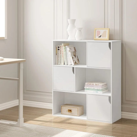 Witte vakkenkast met zes vakken en drie deuren, met boeken en decoratie in een woonruimte
